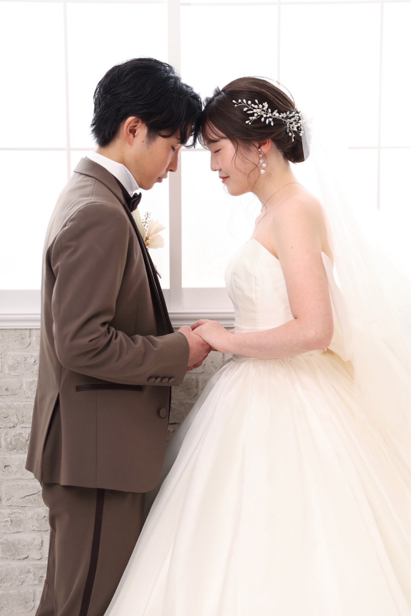 Couple in a wedding dress and tuxedo facing each other in a studio
