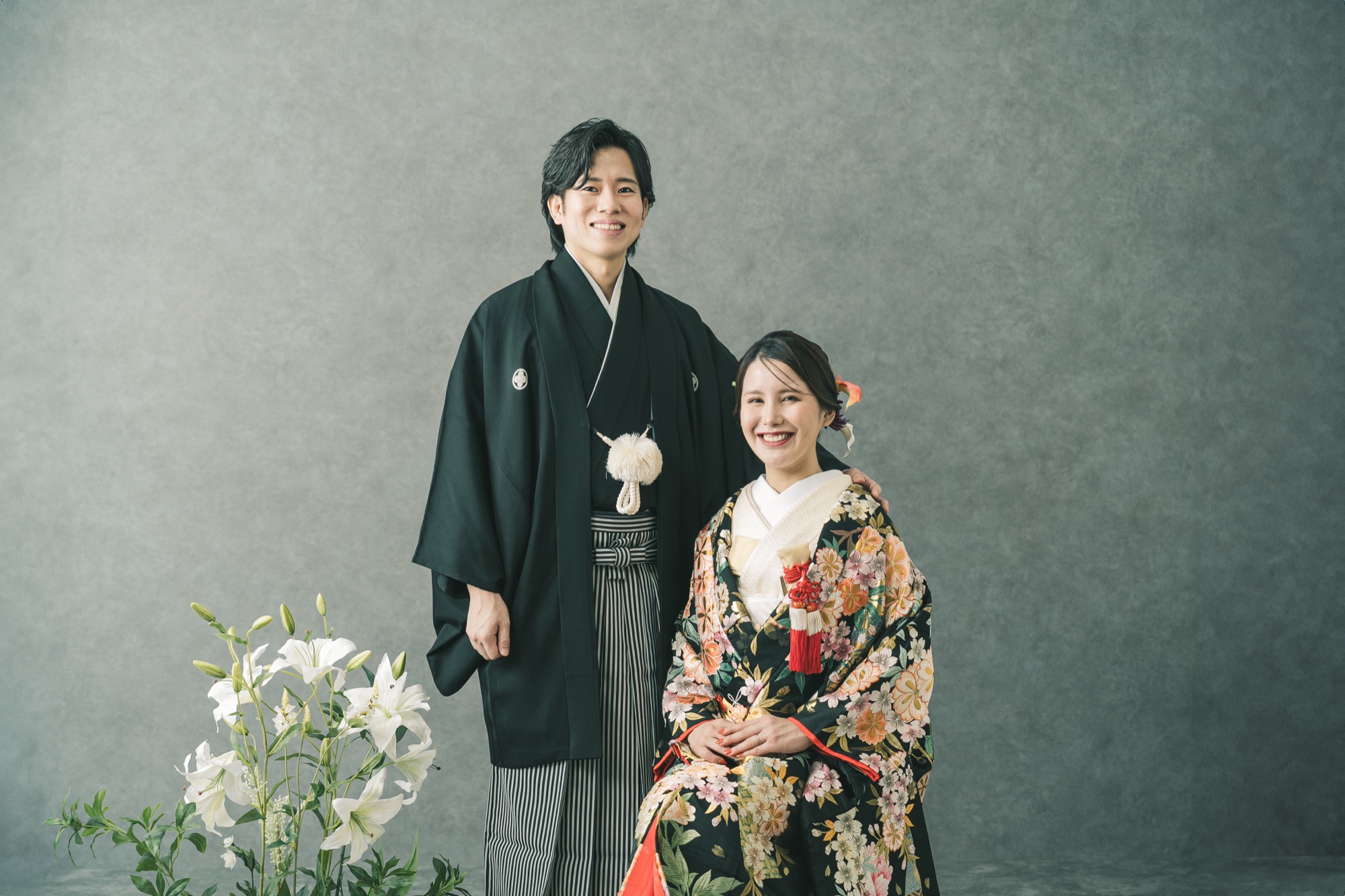 Bride in a colorful uchikake and groom with flowers in a studio