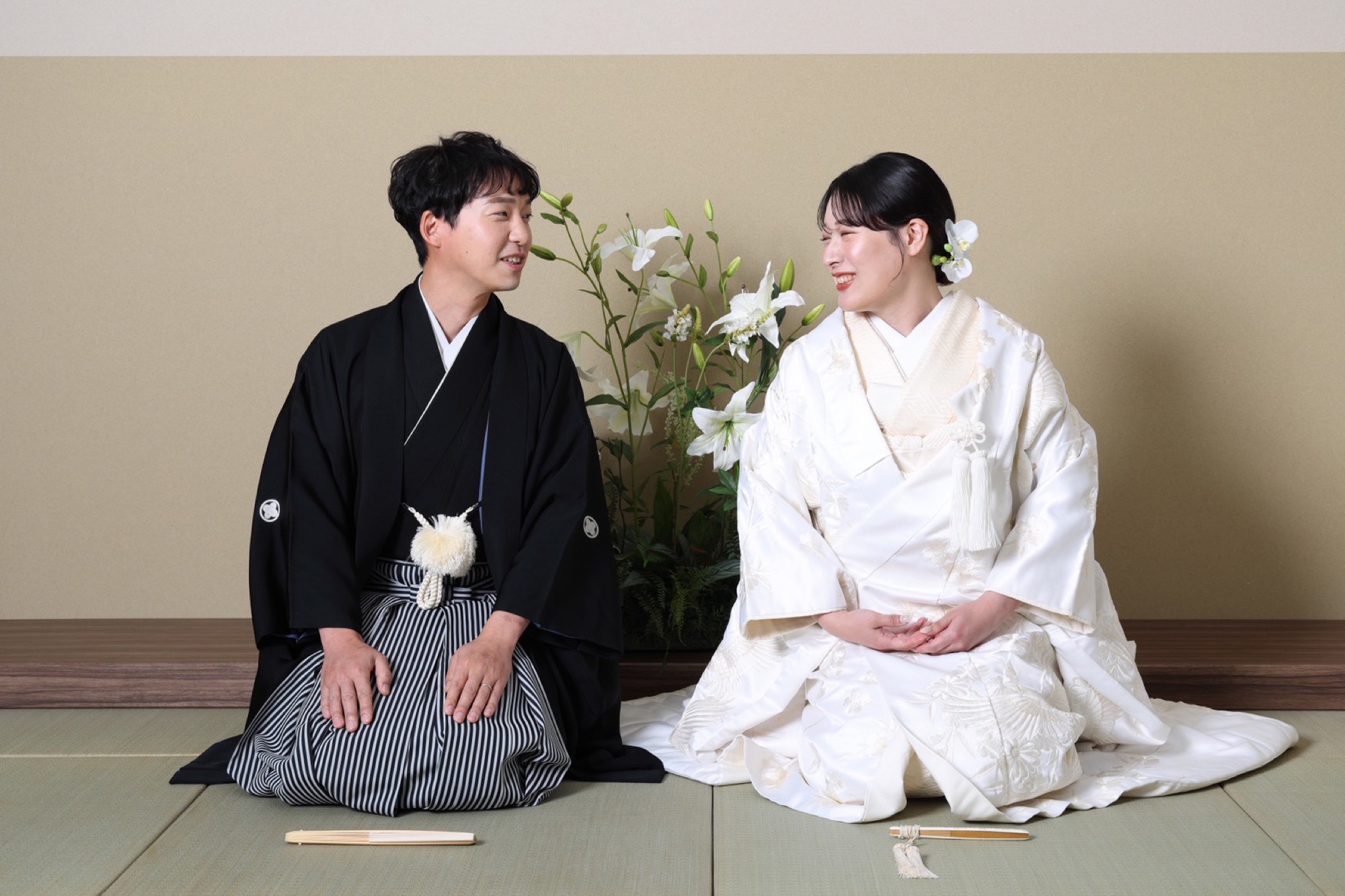 スタジオの畳の上で正座する白無垢の新婦と紋付袴の新郎
