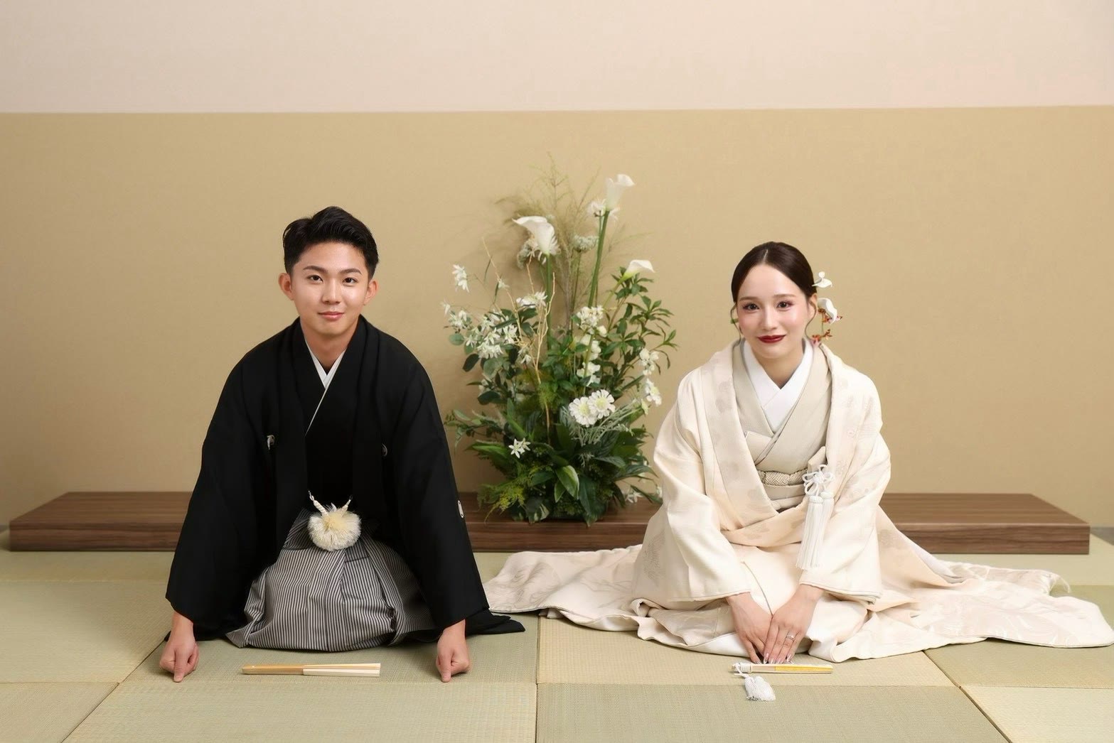 Couple in black montsuki and ivory bridal kimono seated on tatami