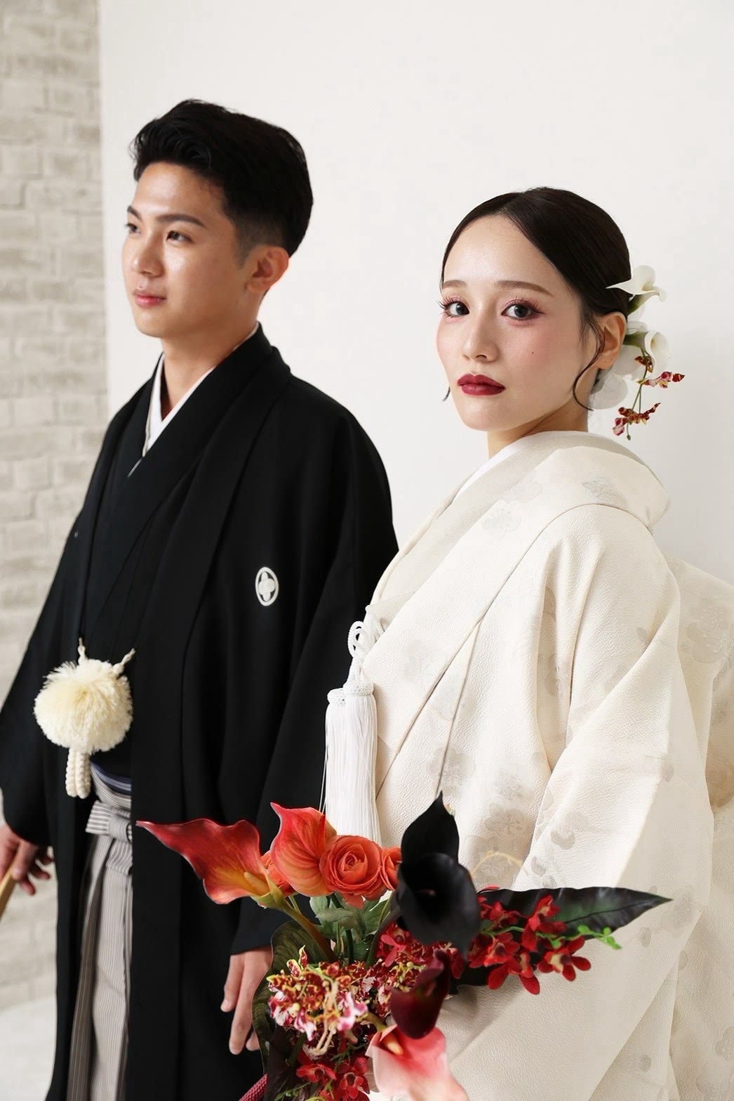 白いレンガ壁のスタジオで白無垢の新婦と黒紋付羽織袴の新郎
