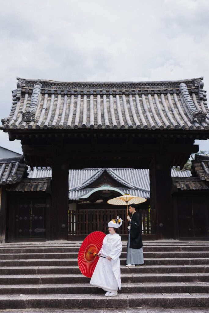 随心院で白無垢と紋付袴の和装の前撮り（門の前の石段と和傘）